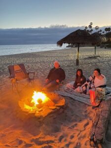 A group of people sitting around a fire on the beach